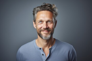 Wall Mural - Portrait of a content man in his 40s smiling at the camera isolated on pastel gray background