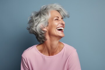 Poster - Portrait of a content woman in her 50s laughing on pastel gray background