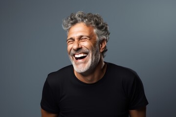 Wall Mural - Portrait of a joyful man in his 50s laughing in pastel gray background