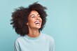 © Markus Schröder - Portrait of a joyful afro-american woman in her 20s laughing while standing against pastel gray background