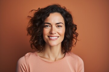 Wall Mural - Portrait of a glad woman in her 30s smiling at the camera isolated in pastel brown background