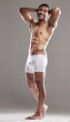 © peopleimages.com - Portrait, man and arms up in underwear for body, wellness and smile in isolated, studio and background as model. Male person, confident and pride for progress as bodybuilder for results in backdrop
