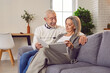 © Studio Romantic - Joyful aged couple sitting on sofa looking their family photo album indulging in happy memories. Smiles on faces relieve happy memories moments captured in each photo happy memories together
