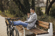 Man Sitting on Bench Next to Bike and Sending A Voice Message