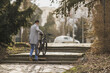 Man Carrying Bicycle Up Stone Steps in Urban Park