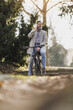 Man Leaning on Bicycle in Urban Park Using Smart Phone