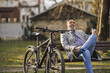 Man With Bike Taking a Coffee Break on a Park Bench