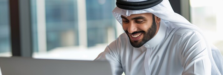 Middle Eastern man dressed in a white kandura working on a laptop, appearing focused but approachable