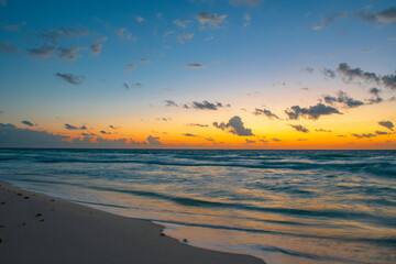 Wall Mural - beach landscape before sunrise with light from behind the cloud and reflection in the ocean