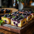 Blueberry cake squares with dusted sugar and fresh berries on a wooden board.