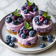 Small cakes topped with purple frosting and fresh berries on a plate.