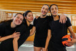 © Zamrznuti tonovi - Four multiracial female volleyball players posing at the net in an indoor hall