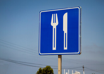 A blue road sign with a large white knife and fork in Rosorito Mexico