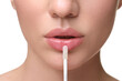 © New Africa - Woman applying lip gloss on white background, closeup