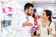 © JackF - Young adult man pharmacist consulting woman customer about products at pharmacy