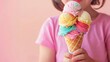 A young girl holds a colorful ice cream cone with three different flavors