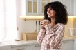 © New Africa - Beautiful young woman in stylish pyjama with cup of drink in kitchen, space for text