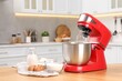 © New Africa - Modern red stand mixer and products on wooden table in kitchen