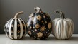Elegant Black and White Painted Pumpkins with Gold Accents on Neutral Backdrop.