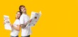 © Pixel-Shot - Young couple reading newspapers on yellow background with space for text