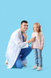 © Pixel-Shot - Male pediatrician examining little girl with stethoscope on blue background