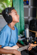 © StanleyRevaldo - A child is recording a song in a home recording studio. A child playing the ukulele sings into a recording microphone