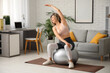 © Pixel-Shot - Happy mature sporty woman with fitness ball training at home