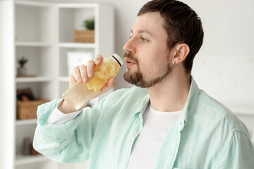 Canvas Print - Young man drinking lemon water at home, closeup