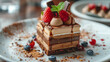 Plate of mini layered dessert cake with brown mousse, chocolate on top.