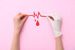 © Pixel-Shot - Female hands with cardiogram and paper blood drops on pink background. World Blood Donor Day