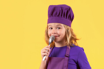 Wall Mural - Funny kid chef cook with spoon, studio portrait. Excited chef cook. Child wearing cooker uniform and chef hat preparing food, studio portrait.