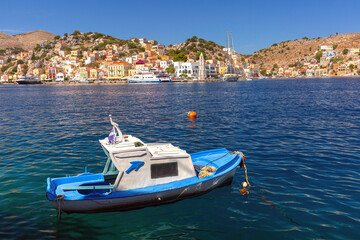 Wall Mural - Serene harbor view with traditional fishing boat on Symi Island, Greece