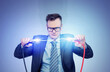 A man in a dark suit and glasses holds two thick wires with clips between which a powerful electrical discharge occurs. On a dark blue background