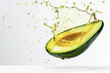 Half of avocado in oil splash flows  on white background. Healthy fats.