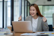 © Surachai - Happy Asian business woman celebrating with laptop happy successful gesture In the modern office Small business idea for starting up