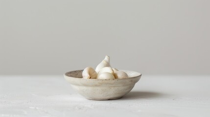 Poster - Garlic placed alone on a small dish with a white backdrop