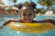 © NE97 - Black overjoyed laughing smiling exited child in swimming pool floating on swimming ring, little girl having fun on family summer vacation in tropical hotel resort.