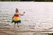 Child in colorful dress joyfully jumping into lake water