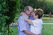 Elderly couple embracing joyfully in a garden at sunset