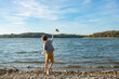 young boy throws rock into lake with waves on a sunny day