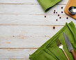 © OceanProd - White wooden table background  with green tablecloth and metal fork knife cooking utensils