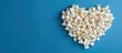 © HN Works - Heart shaped popcorn displayed on a blue background with ample copy space for additional content