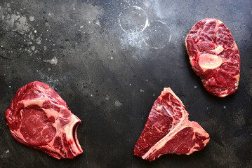 Wall Mural - Raw organic marbled beef steaks : ossobuko, rib eye ( cowboy ) , T - bone. Top view with copy space.