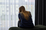 Fototapeta  - Kobieta w depresji siedzi w nowym mieszkaniu i patrzy przez okno