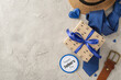 A festive arrangement for Father's Day featuring a straw hat, gift box with a blue ribbon, polka dot tie, and a 'Happy Father's Day' sign on a textured concrete surface