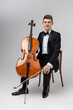 Young male artist sitting on chair and playing contrabass