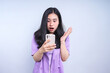 © Gatot - Surprised Young Woman Using Smartphone Isolated on Grey Background