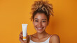 © Volodymyr - Smiling woman holding skincare product with curly hair against orange background. Copy space. Generative AI