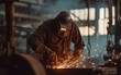 Worker in protective welding mask and gloves grinds metal, sparks scattering.