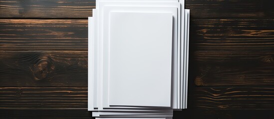 Poster - A mock up of blank paper sheets for a brochure is stacked on a black wooden background creating a copy space image